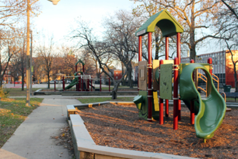 Playground with green and red slide on a fall afternoon.