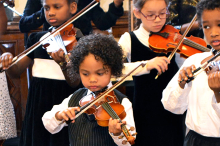 Young musicians playing violins in a concert.

