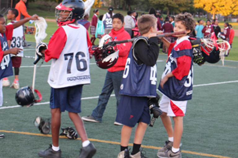 Young lacrosse players gather on the field.
