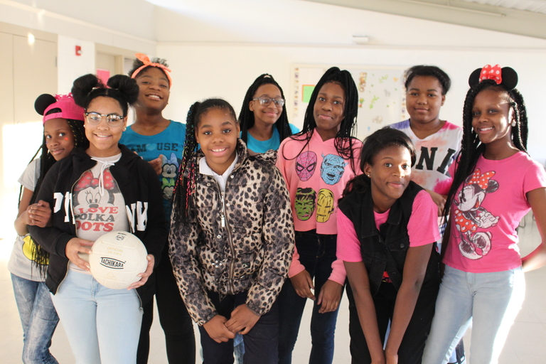 Group photo of girls wearing colorful shirts and some with mouse ears.