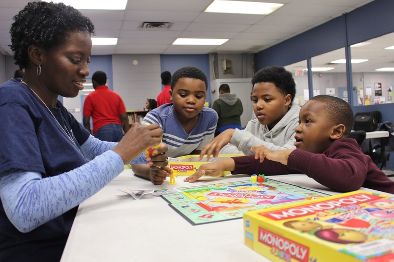 A woman and three children play Monopoly Junior.