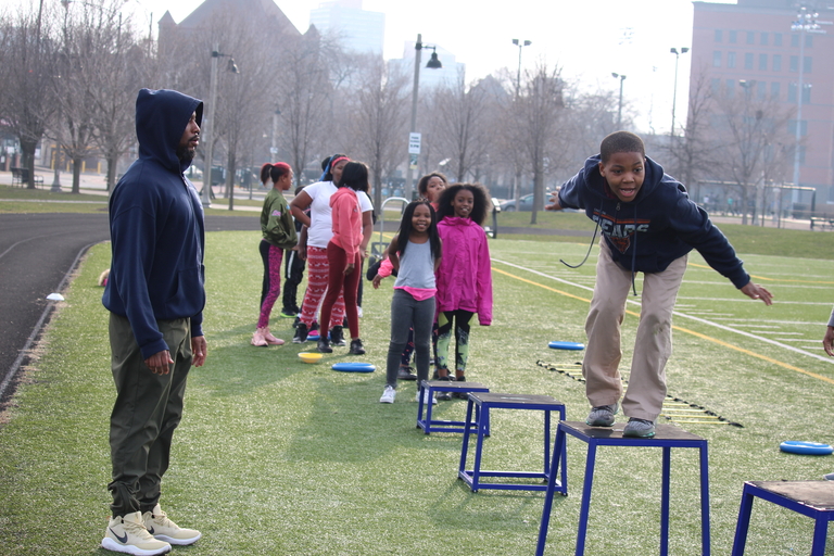 Child balances on short blue hurdles during outdoor activity.