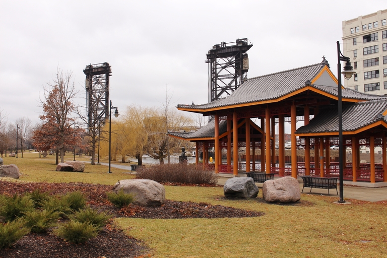Chinese pavilion in a park with lift bridges in the background.