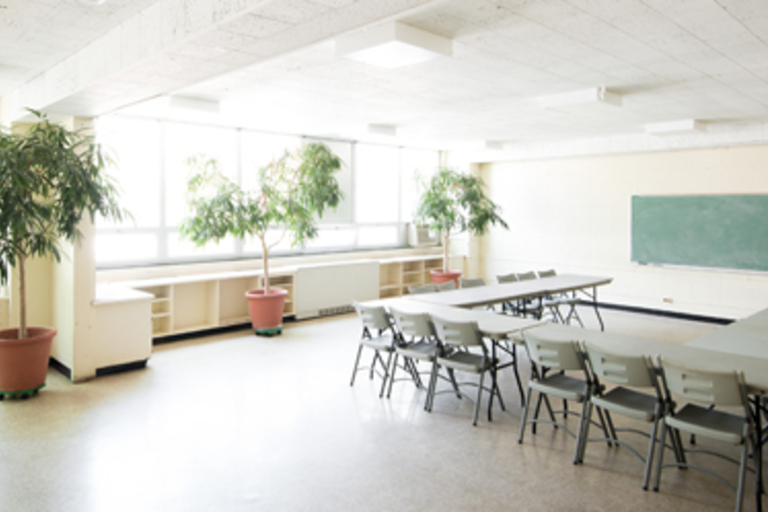 Bright classroom with folding tables and chairs arranged in a U-shape.