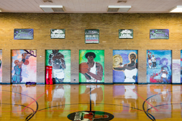 Indoor basketball court with colorful murals of athletes.