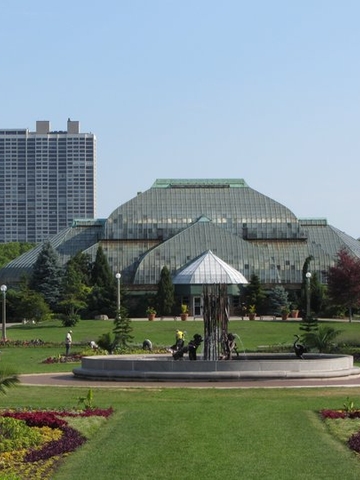 Garfield Park Conservatory in Chicago with flower beds and fountain in the foreground.