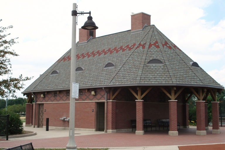 Octagonal brick and wood park shelter with gray tiled roof.
