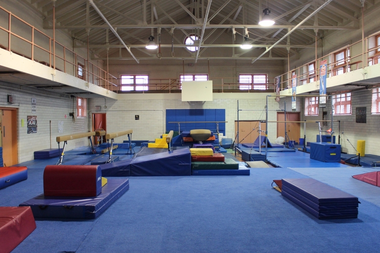 Gymnastics equipment sits on blue mats in a gym.