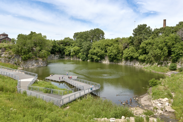 Visitors enjoy a metal walkway and floating dock on a small quarry pond.