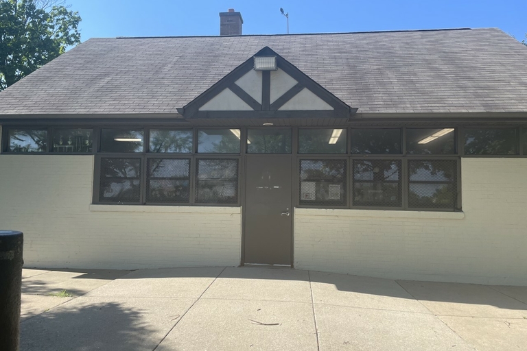 Small white brick building with a dark brown door and decorative cross beams.