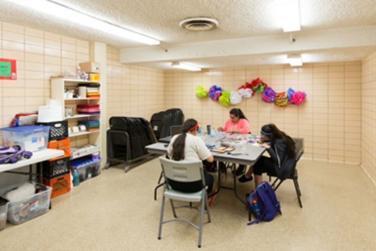 Students crafting at a table in a classroom.