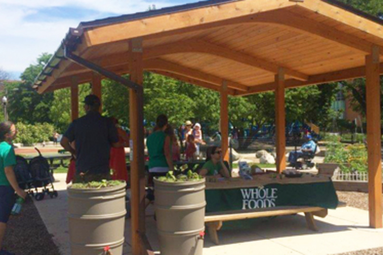 People gather at a picnic shelter in a community garden.
