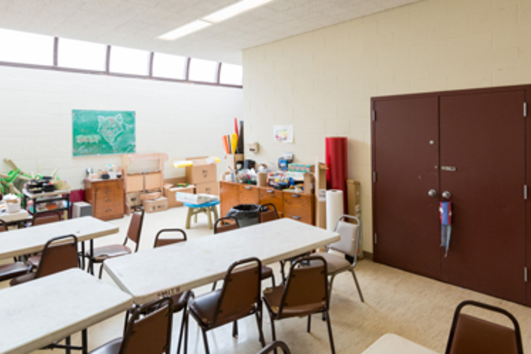 Classroom with folding tables and chairs, storage, and double doors.