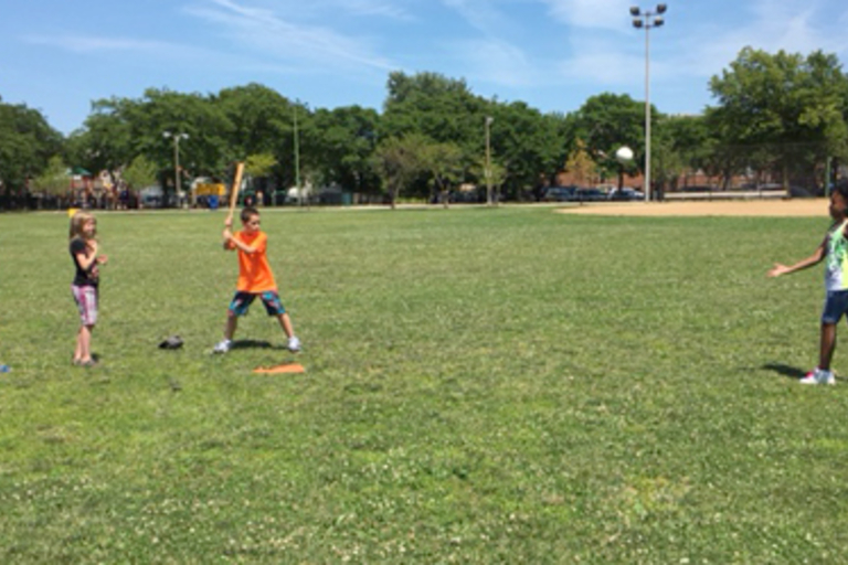 Children playing baseball in a park.
