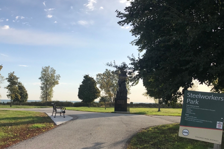 Steelworkers Park with a statue, park bench, and sign near Lake Michigan.