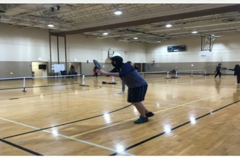 People playing pickleball in a gym.