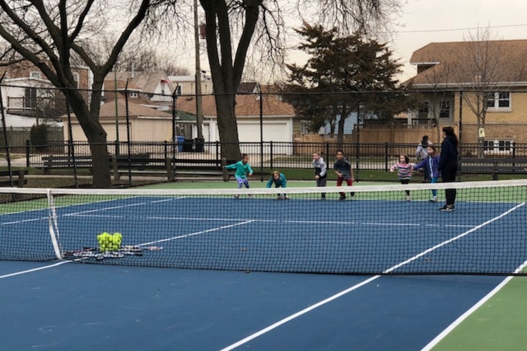 Children learning tennis on a blue court.