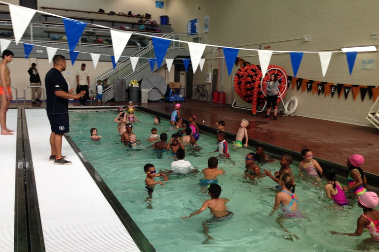Children participate in a swim lesson at an indoor pool.