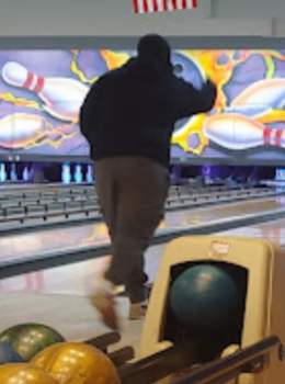 Person bowling, ball rolling down lane.