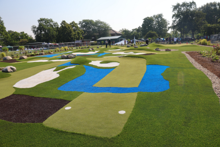 Vibrant mini golf course with green turf, blue water features, and white sand traps. People play in the background.