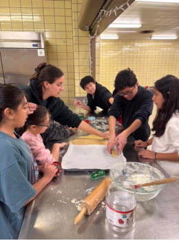 Teenagers making cookies on a metal table.