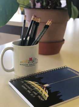 Pencils in a mug, notepad, and potted plant on a desk.