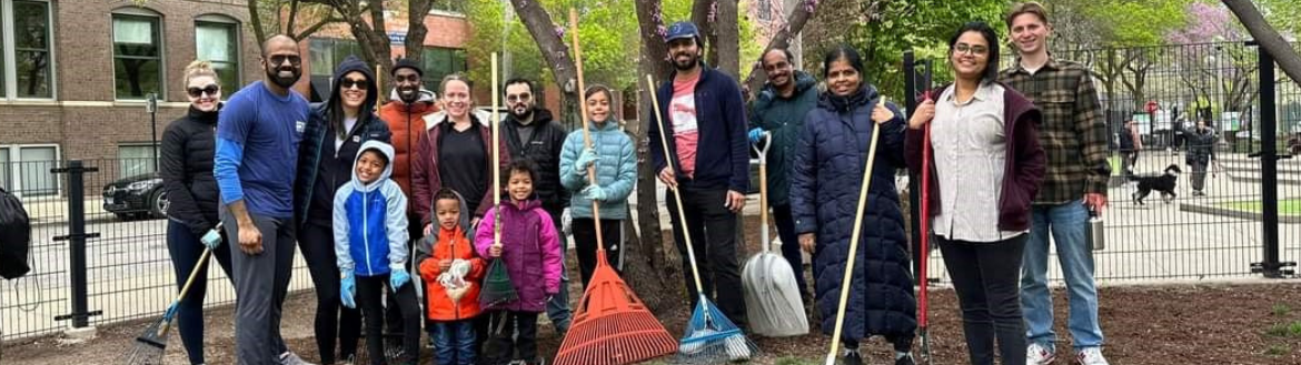 Group of diverse volunteers holding rakes and shovels as part of a clean up event at a park.