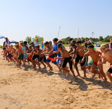 Children running on the beach at a Junior Lifeguard competition.
