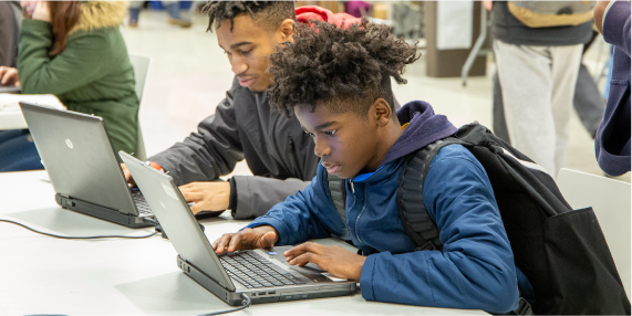 A couple of teens are working on laptops