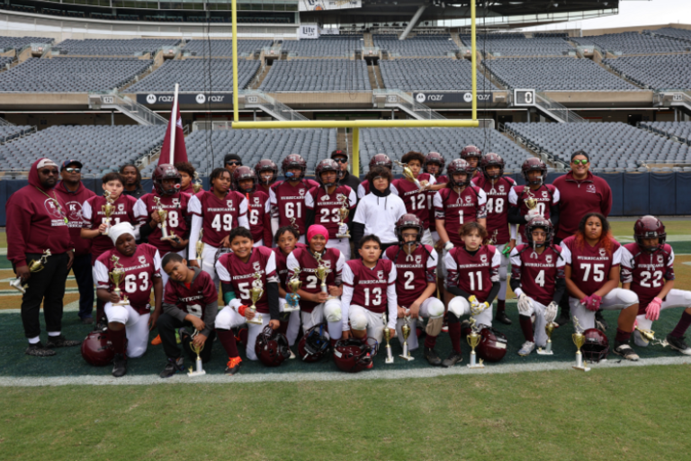 Youth football team poses with trophies.