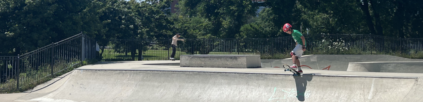 Child skateboarder atop ramp at skatepark.