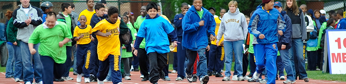 Children and adults run on a track during a race.