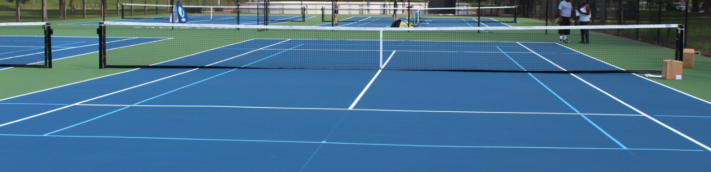 Blue and green tennis courts on a sunny day.