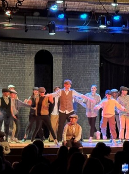 Students perform a musical number on stage.