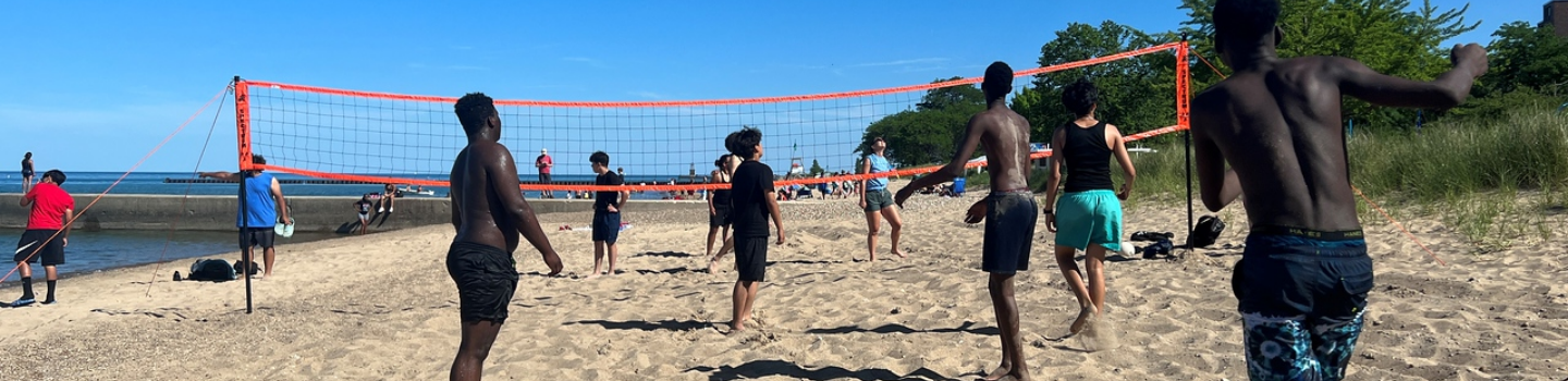 People play beach volleyball on a sunny day.