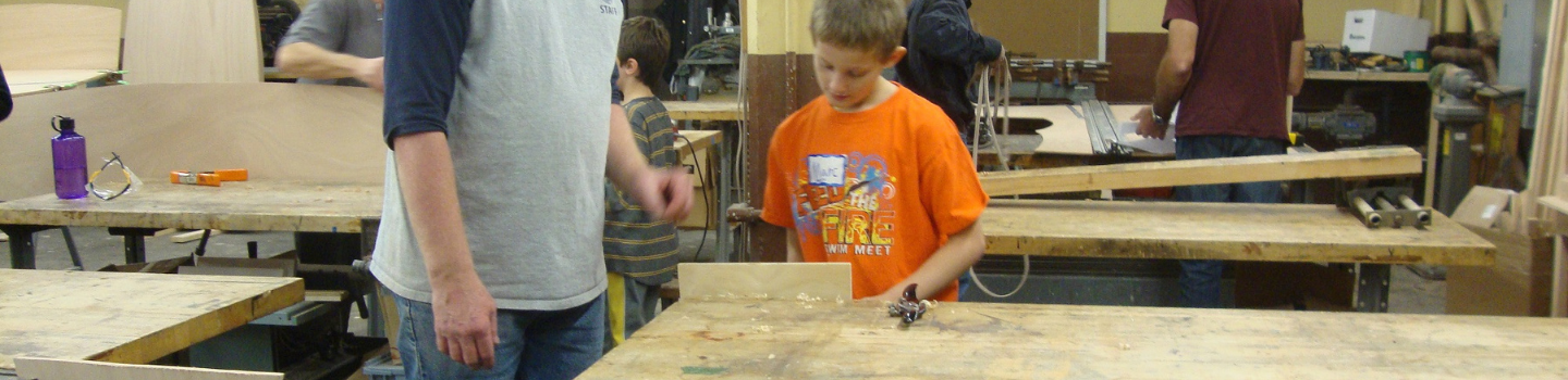 Children and adults working with wood in a workshop.